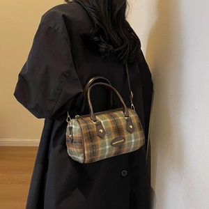 Sac Boston en laine à carreaux avec lanières en cuir marron porté par un mannequin