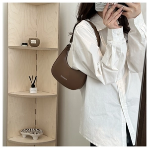 Detailed close-up of dark brown crescent hobo bag with Fashion logo on the shoulder