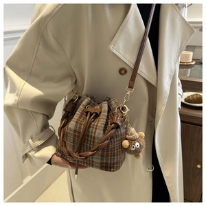 Detail view of plaid plush bucket bag with leather drawstring and cute monster charm