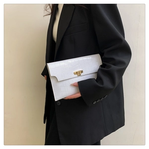 Detail view of a white crocodile embossed envelope clutch bag with gold metal clasp