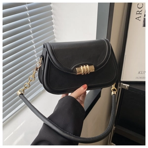 Detail of black leather saddle bag featuring a bold cylindrical gold metal buckle closure