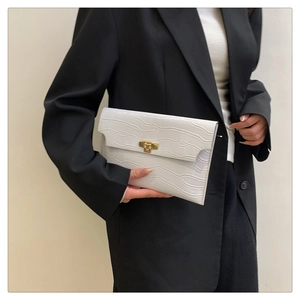 Detail of white crocodile pattern envelope clutch bag with golden metal buckle