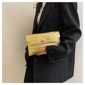 Close-up of golden envelope clutch bag with crocodile pattern and square metal lock