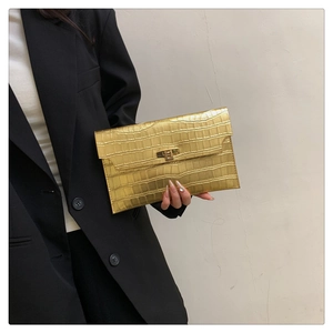 Detailed view of a gold crocodile embossed envelope clutch bag with metal lock closure