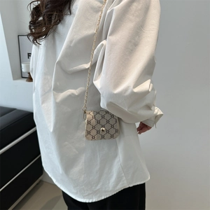 Miniature beige chain crossbody bag with classic pattern shown on model in modern room