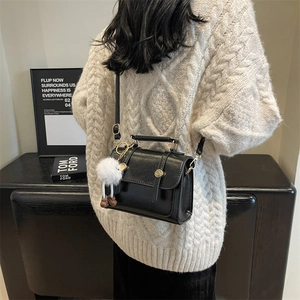 Classic black leather crossbody box bag with handle and plush decorative charm