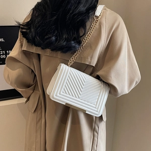 Chic white quilted crossbody bag with gold chain strap worn with a khaki trench coat