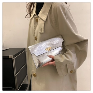 Detail of silver crocodile pattern clutch with gold turn-lock clasp shown by model