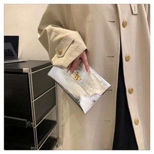 Detail of silver crocodile-embossed envelope clutch bag with gold square twist lock