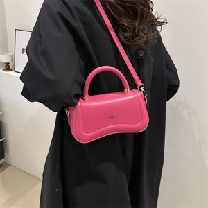 Sac à bandoulière rose tendance avec logo doré sur manteau noir pour femme