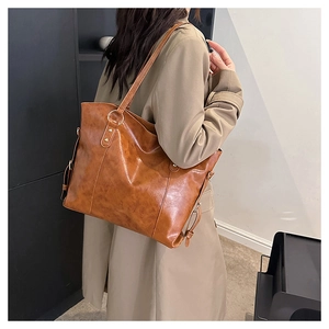 Detail view of a large caramel brown leather tote bag with elegant gold hardware rings