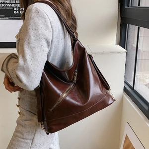 Grand sac cabas rétro marron foncé en similicuir brillant porté par un mannequin élégant