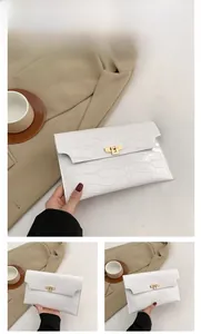 Detail view of white crocodile pattern envelope clutch with gold twist lock