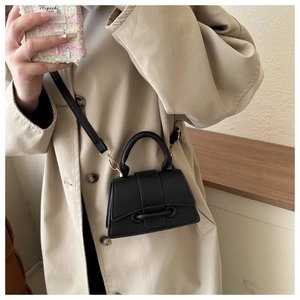 Detail of black lychee grain leather mini bag with gold hardware and top handle