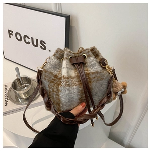 Detail of checkered plush bucket bag featuring brown leather woven strap and bear charm