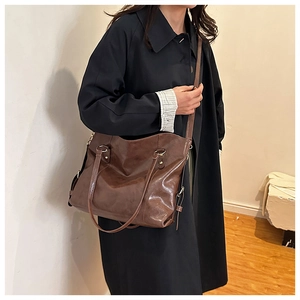 Detail of a dark brown vintage tote bag worn over the shoulder showing the large capacity