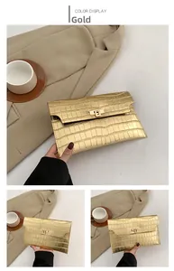 Detail of gold envelope clutch bag featuring crocodile pattern and metallic twist lock