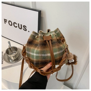Detail of plaid tweed bucket bag with woven handle and plush doll charm accessory