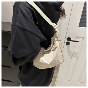 Detail of beige nylon crescent bag with adjustable wide shoulder strap and textured fabric