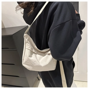 Side view of cream-white minimalist tote bag with wide strap and crinkled texture