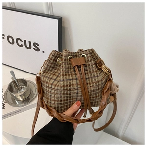 Detail of vintage plaid bucket bag with brown leather drawstring and woven handle