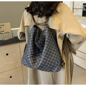 Detailed view of grey tote bag with clover patterns and brown leather straps