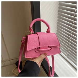 Detail of pink lychee leather mini handbag with gold hardware and circular top handle