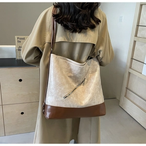 Detail view of large two-tone tote bag with vintage texture on a trench coat model