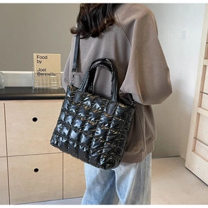 Détail d'un sac cabas noir matelassé avec texture brillante et bandoulière réglable