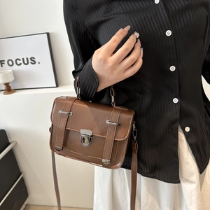Détail du sac bandoulière vintage en cuir marron avec boucle argentée et poignée
