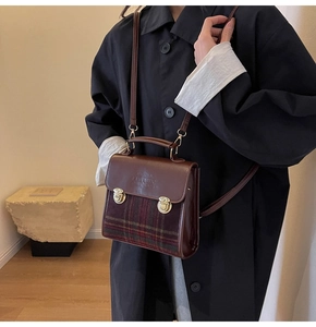 Detail of vintage brown leather handbag with British plaid fabric and gold buckle clasp