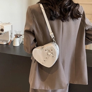 Sac bandoulière blanc en forme de cœur avec rivets et bandoulière réglable sur modèle