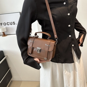 Détail d'un sac bandoulière vintage marron avec fermoir tournant argenté et poignée