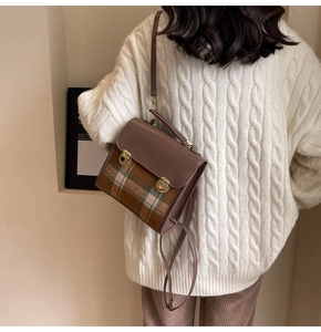 Detail of vintage plaid messenger bag featuring brown leather trim and metal buckles