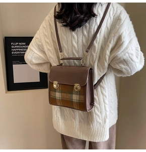 Detail of the vintage brown leather and plaid fabric backpack with a gold metal buckle closure