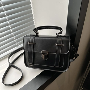 Détail du sac bandoulière noir en similicuir avec boucles argentées et rabat