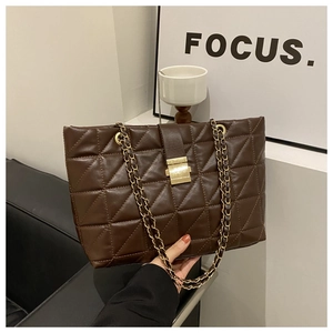 Détail d'un grand sac cabas matelassé marron foncé avec bandoulière en chaîne dorée chic