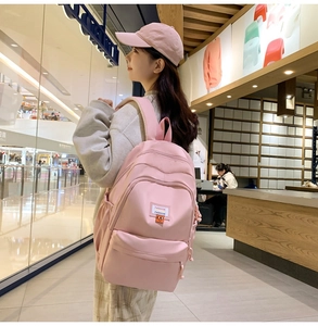 Pink casual backpack side view on model featuring large capacity and a stylish patch