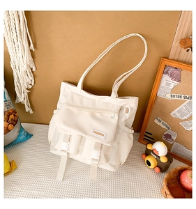 Détail du sac messager en toile blanc cassé avec fermetures éclair et boucles réglables