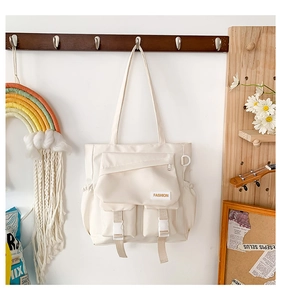 Détail du sac en toile blanc crème avec plusieurs poches, boucles et fermetures