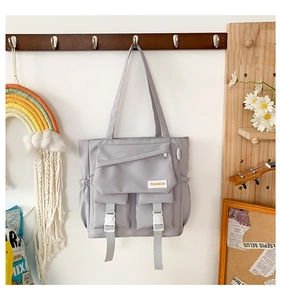 Vue détaillée du sac fourre-tout gris clair avec poches à boucles et étiquette de mode