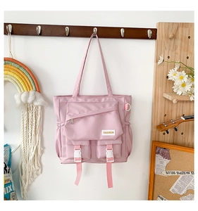Vue détaillée du sac bandoulière en toile rose avec poches et boucles blanches
