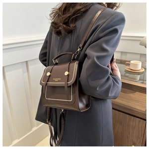 Close-up of vintage brown PU leather backpack featuring brand logo and beige bead trim