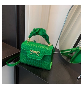 Detail of green crocodile texture bag with gold bow and ruched cloud handle