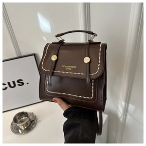 Detail of dark brown leather backpack featuring pearl trim and golden buckle closure