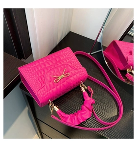 Detail of rose red square bag with quilted texture and golden bow-knot metal clasp
