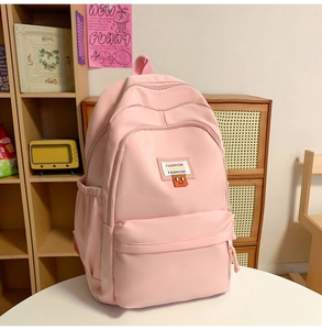 Detail of pink nylon backpack with multiple zipper pockets and fashion label on wooden shelf