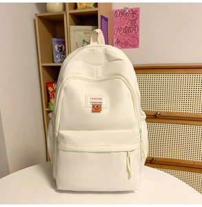 Close-up of minimalist white canvas backpack with orange smile patch in a cozy home setting