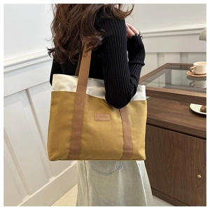 Detail of canvas tote bag showing two-tone contrast stitching and leather fashion label