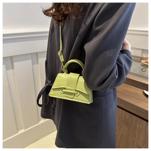 Detailopname van de grasgroene mini-handtas met krokodillenpatroon en trapeze-vorm